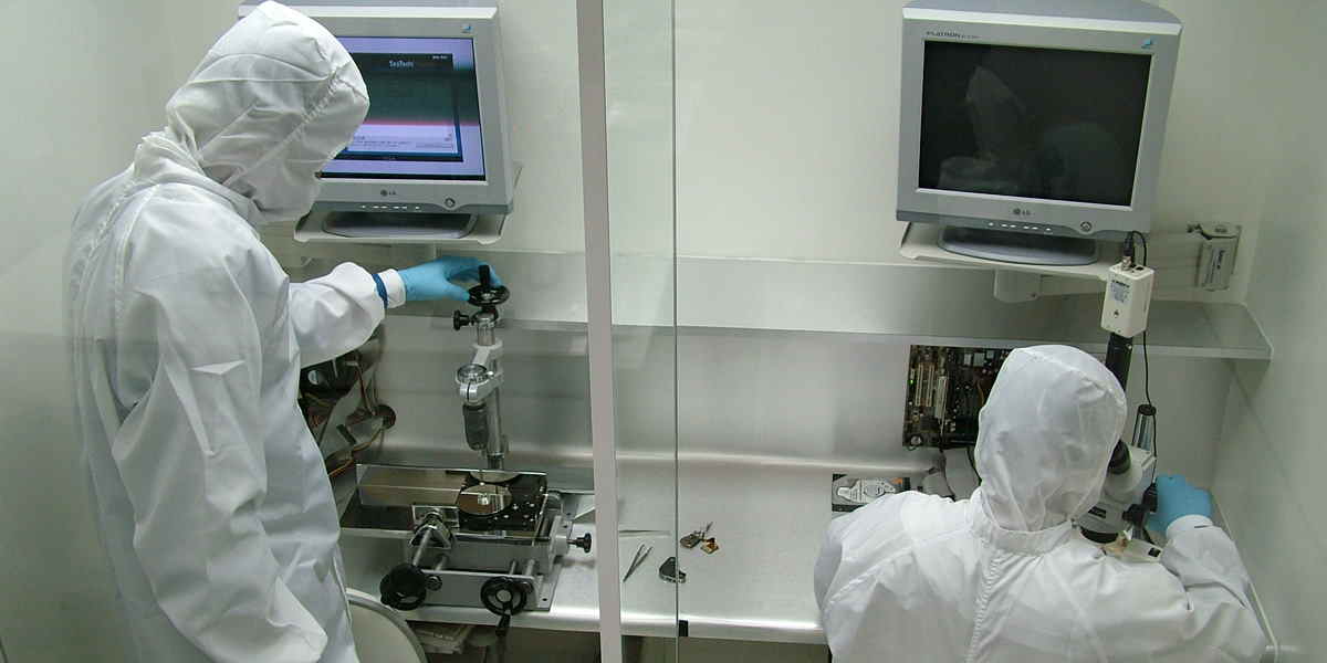 Sala Limpa Classe 100 da DATADISK em 2003 com dois engenheiros trabalhando em processos técnicos de recuperação de dados.